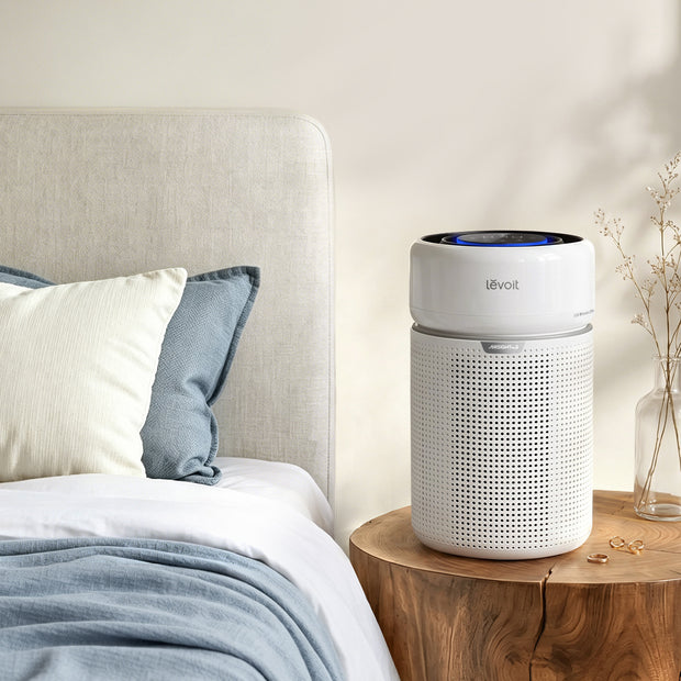 White cylindrical air purifier with blue-lit top display and perforated grille